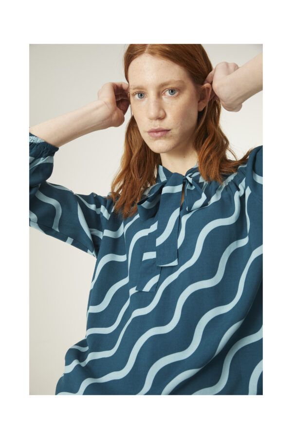 Top con estampado geométrico de ondas. Con cuello lazada y manga larga. Canesú frontal y trasero con detalle de frunces. De Compañia Fantastica