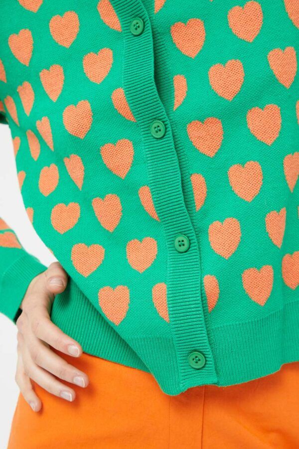 Cárdigan de punto intarsia de color verde con estampado de corazones naranjas. Con cuello redondo y manga larga. Cierre frontal con botones. Compañia Fantastica