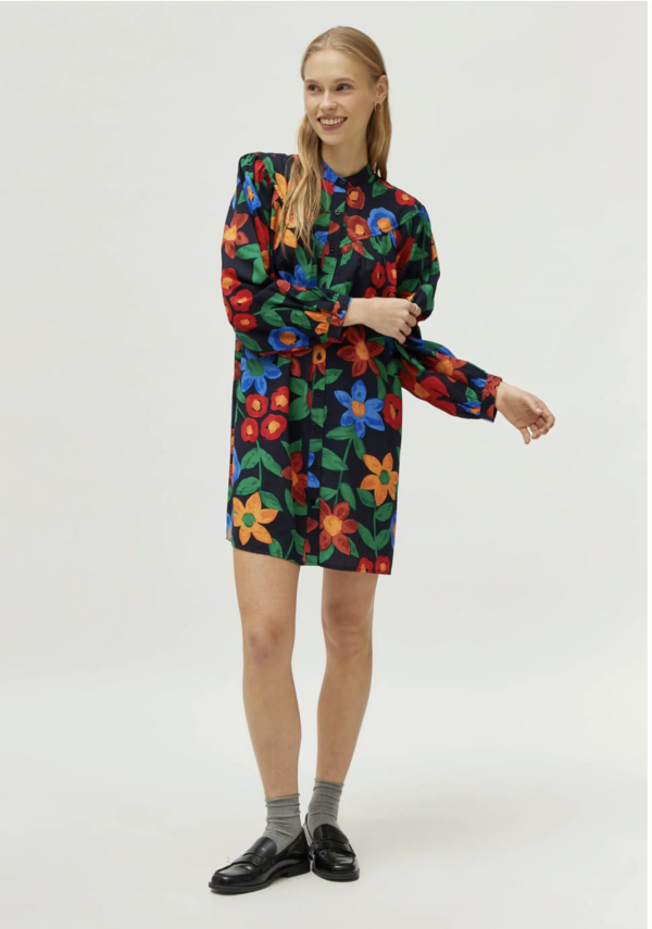 Vestido corto en crepé de viscosa con estampado de flores multicolor. Con cuello mao y manga larga. Cierre frontal con botones. Detalle de corte en el pecho.