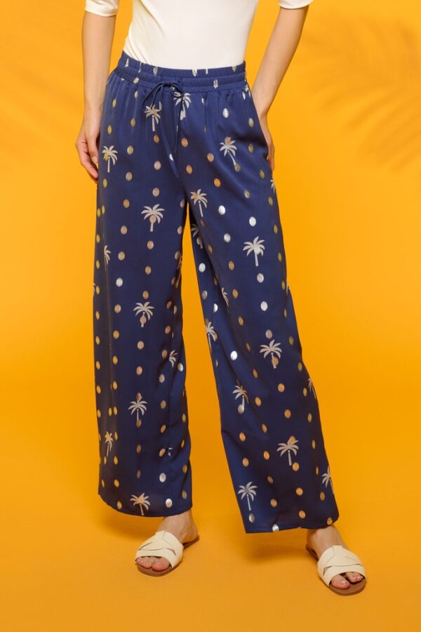 Pantalón fluido azul con estampado de palmeras y lunares en plateado. Disponible también en nuestra tienda física en Badajoz, en el Casco Antiguo.