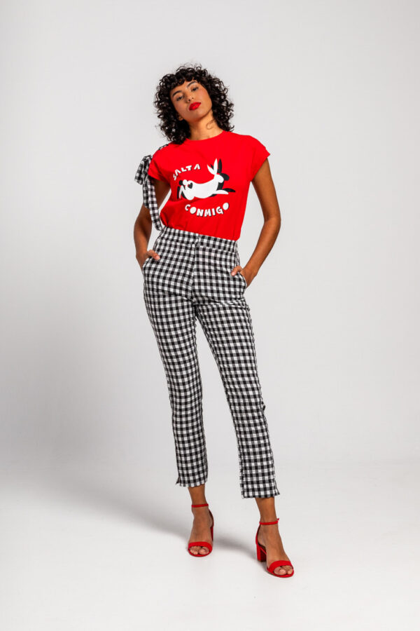 Camiseta de algodón con detalle en uno de sus hombros un una lazada. Con impresión de conejo en blanco saltando y con mensaje. También puedes encontrarlo en nuestra tienda física.