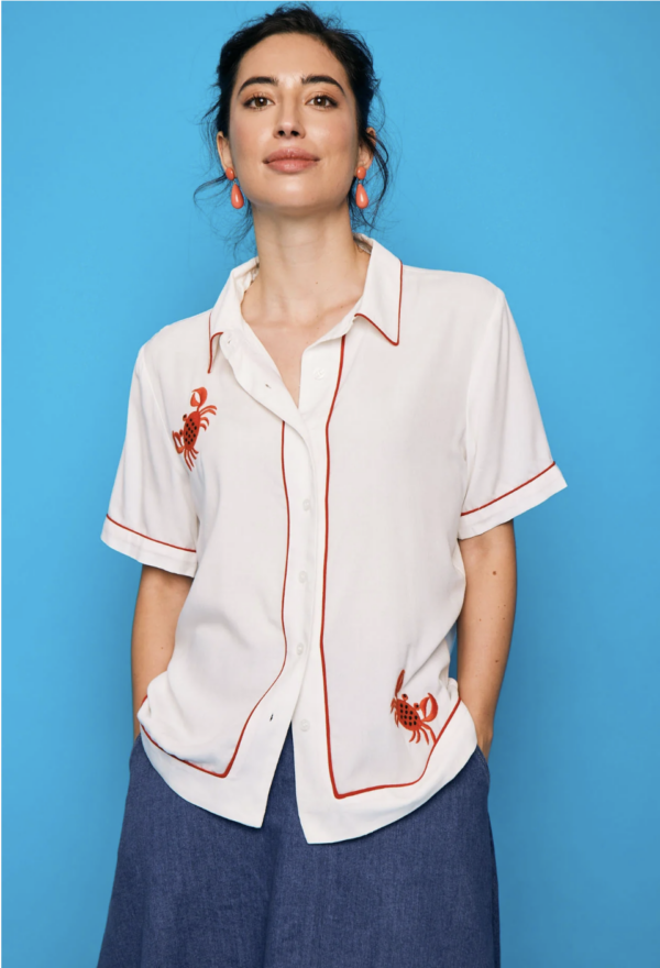 Camisa blanca estilo retro con ribetes rojos y cangrejo bordado en rojo. Diseño fresco y con personalidad. Encuéntrala en Dulce Locura, moda en Badajoz.