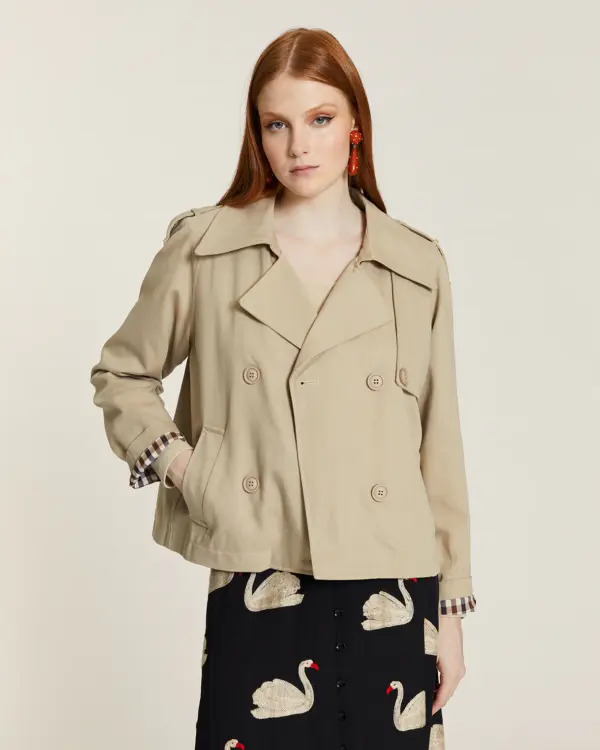 Gabardina corta de color beige con forro de cuadros. Disponible en Dulce Locura, tienda de moda en Badajoz.