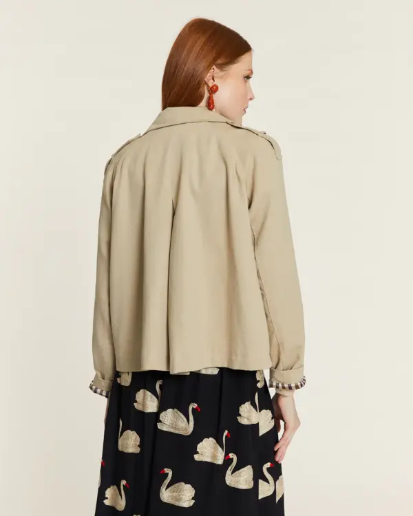 Gabardina corta de color beige con forro de cuadros. Disponible en Dulce Locura, tienda de moda en Badajoz.