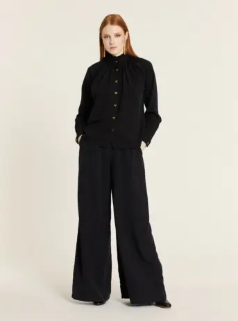 Pantalón fluido Tencel negro palazzo de pierna ancha y caída recta con cintura ajustada y bolsillos laterales. Disponible en Dulce Locura, tienda de moda en Badajoz.