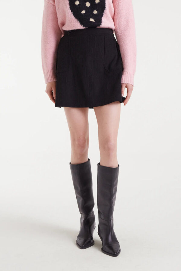 Falda corta de pana negra de Compañía Fantástica, tiro medio, bolsillos laterales y cremallera oculta. Disponible en Dulce Locura, tienda de moda en Badajoz.