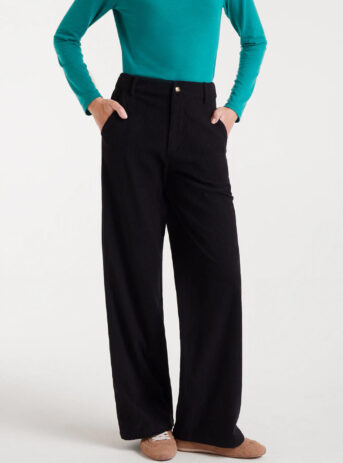 Pantalón de pana negro con tiro medio, pernera recta, bolsillos laterales y cierre de cremallera y botón metálico. Disponible en Dulce Locura, tienda de moda en Badajoz.