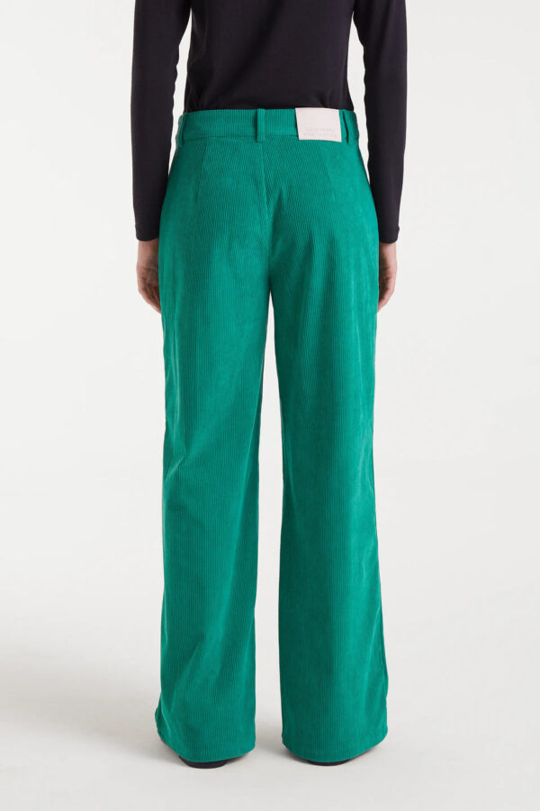 Pantalón de pana verde con tiro medio, pernera recta y cierre de cremallera y botón metálico. Disponible en Dulce Locura, tienda de moda en Badajoz.