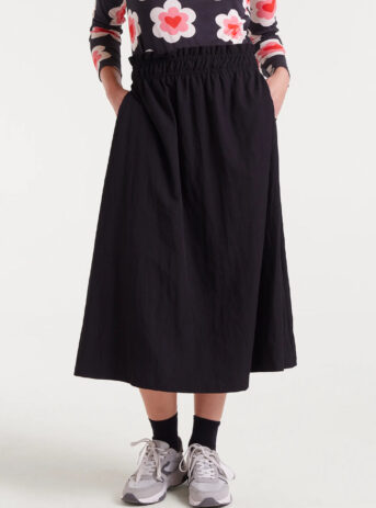 Falda midi negra en tejido technical con cintura fruncida de tiro medio y bolsillos laterales. Disponible en Dulce Locura, tienda de moda en Badajoz.