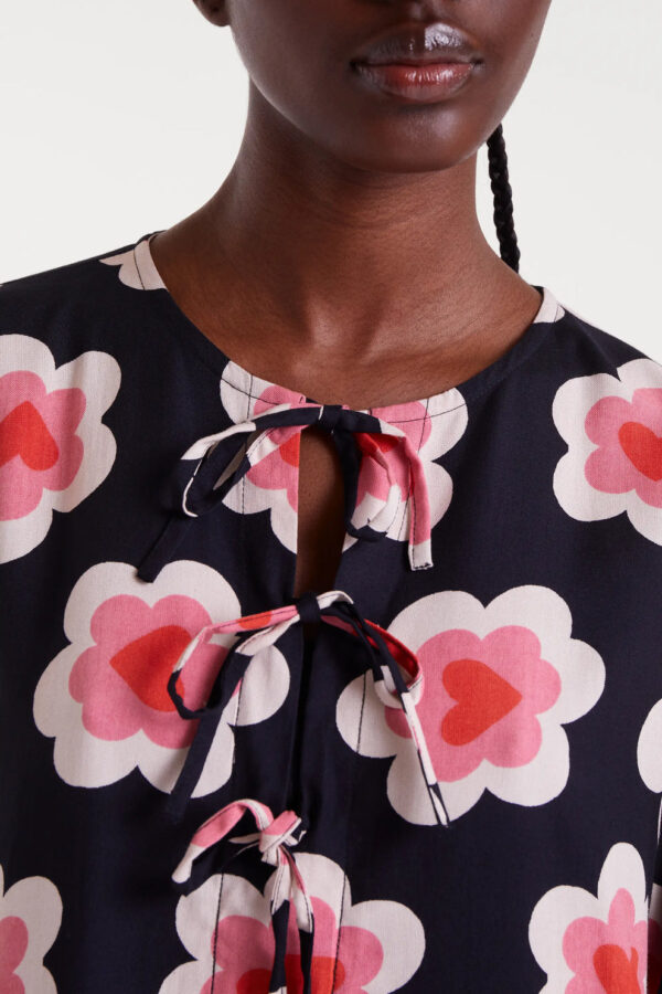 Vestido corto con estampado Sweetheart, cuello barco, escote anudado, manga larga con puño elástico y bolsillos laterales. Disponible en Dulce Locura.