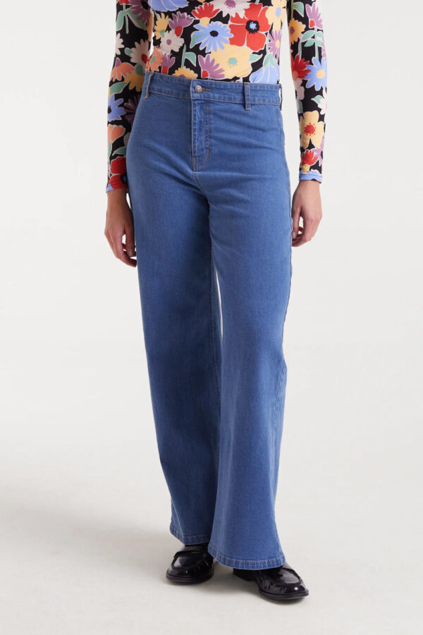 Pantalón vaquero azul de mujer en denim elástico con tiro alto, pernera recta y cierre de cremallera y botón. Disponible en Dulce Locura, tienda de moda en Badajoz.