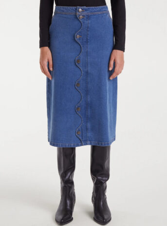 Falda midi azul de tejido denim elástico con tiro alto, cierre frontal de botones y detalle ondulado. Disponible en Dulce Locura, tienda de moda en Badajoz.