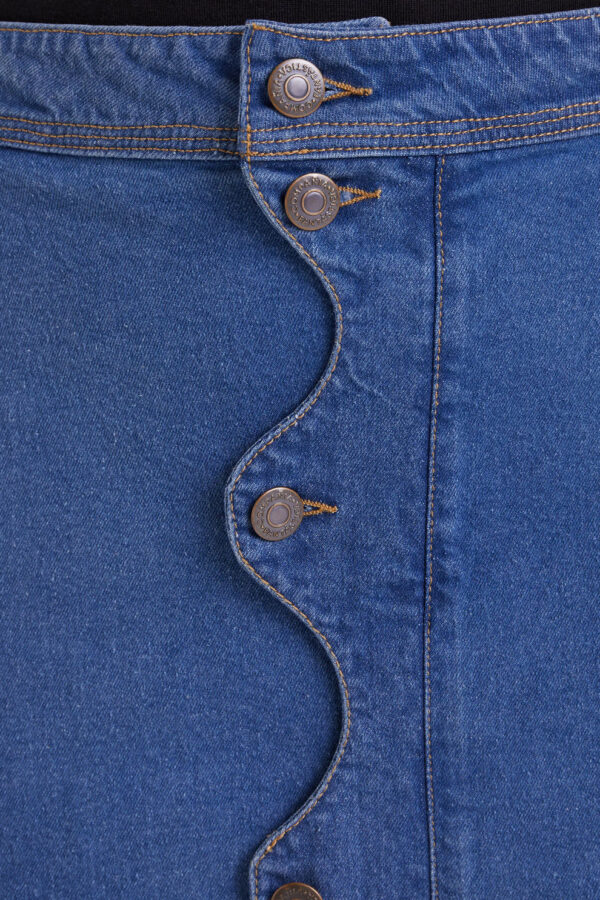 Falda midi azul de tejido denim elástico con tiro alto, cierre frontal de botones y detalle ondulado. Disponible en Dulce Locura, tienda de moda en Badajoz.