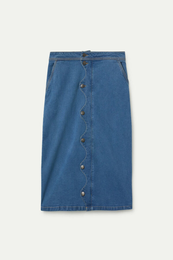 Falda midi azul de tejido denim elástico con tiro alto, cierre frontal de botones y detalle ondulado. Disponible en Dulce Locura, tienda de moda en Badajoz.