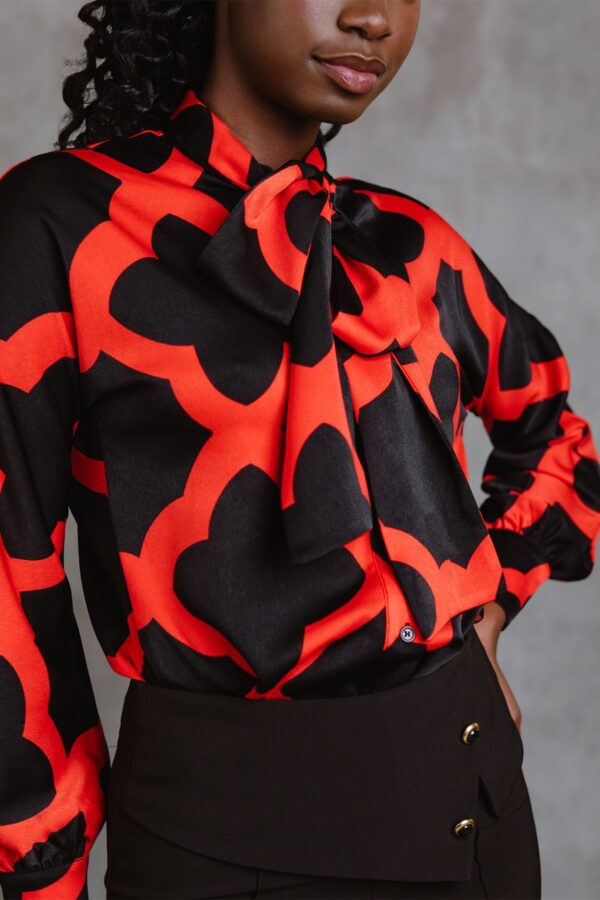 Red Bettina Top, blusa de manga larga con lazada al cuello, botones frontales y estampado mosaico rojo. Disponible en Dulce Locura, tienda de moda en Badajoz.