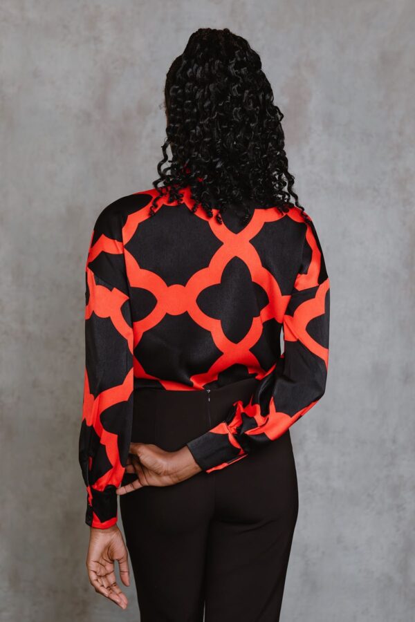 Red Bettina Top, blusa de manga larga con lazada al cuello, botones frontales y estampado mosaico rojo. Disponible en Dulce Locura, tienda de moda en Badajoz.